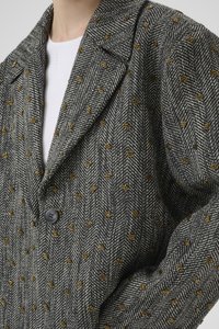 Vlněný kabát s houndstooth vzorem v černobílé barvě se zlatými akcenty, se záložkovým límcem, uzavíráním na jeden knoflík a texturovanou tkaninou.
