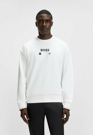 White sweatshirt with "BOSS" logo in black above three colored circles. Features a crew neck and ribbed cuffs. Paired with black pants.