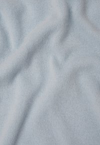 Tissu tricoté bleu clair avec une texture douce, présentant un motif lisse et uniforme avec de légères variations d'ombrage.