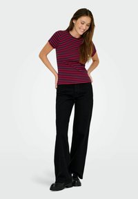 Rød og marineblå stribet kortærmet t-shirt, parret med sorte flagrende bukser og klumpede platform-sko. Glat stof, afslappet design.
