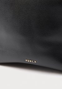 Geantă de mână din piele neagră cu suprafață texturată, având un logo „FURLA” auriu embossat în colțul de jos.