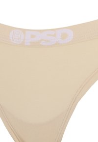 String beige avec texture lisse. Ceinture élastique blanche avec le logo "PSD". Design simple, sans motifs supplémentaires.