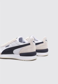 Zapatillas blancas y azul marino con parte superior de ante y malla, acentos texturizados, cierre de cordones y suela de goma con una franja contrastante.