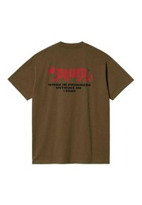 Camiseta de algodón marrón con mangas cortas. La parte trasera presenta un texto gráfico rojo, incluyendo "Carhartt" y un logo de un gato, junto con "WORK IN PROGRESS."
