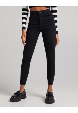 Høj talje sorte denimjeans med slim fit, der har knaplukning, fem lommer og diskret syninger. Glat tekstur, ingen mønstre.