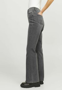 Jeans a zampa d'elefante in denim grigio con vita alta, cinque tasche e dettagli cuciti. Abbinati a scarpe chunky nere con plateau.