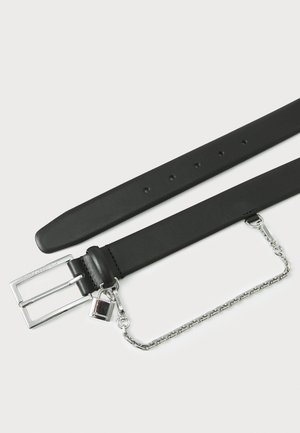 Cinturón de cuero negro con hebilla de doble anclaje plateada, detalle de cadena y charm extraíble. Textura suave con agujeros espaciados de manera uniforme.
