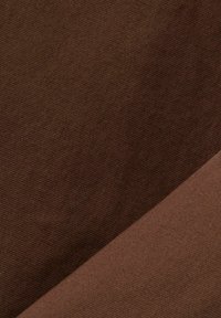 Dettaglio ravvicinato di due campioni di tessuto marrone sovrapposti, che mostrano diverse texture e tonalità.