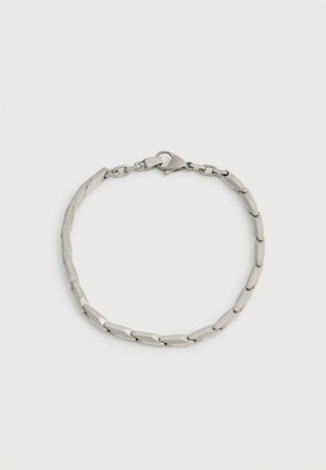 Zapestnica iz kovine srebrne barve z rektangelskimi povezanimi segmenti in zapiranjem na zaponko v obliki rakove klešče na belem ozadju.