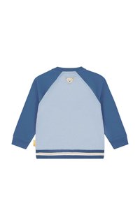 Lys blå og marineblå langærmet skjorte med et lille bamse-patch nær kraven og stribet trim langs bundkanten.