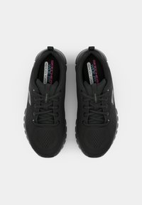 Schwarze Sport-Schuhe mit einem Obermaterial aus Mesh, runder Zehenpartie, strukturierten Sohlen und Memory-Schaum-Einlegesohlen. Verfügt über Schnürsenkel und eine Markenkennzeichnung an der Seite.