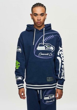 Marineblauw sweatshirt met Seahawks-logo en de tekst "Emerald City". Heeft witte stripes op de manchetten en onderrand, en groene accenten op de mouwen.