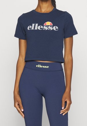 Námořnická modrá zkrácená trička s šedým logem "ellesse" a barevným akcentem nahoře; doplněné námořnickými legínami s žlutým logem na pásku.