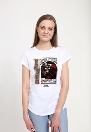 Hvid bomulds T-shirt med et grafisk print af Doctor Strange i rød og sort, med dekorative kanter og tekst i forskellige skrifttyper.