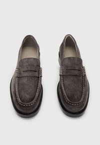 Grå mocka loafers med strukturerad yta, upphöjda sömmar och en kontrasterande svart gummisula. Rund tå och design för att glida på.