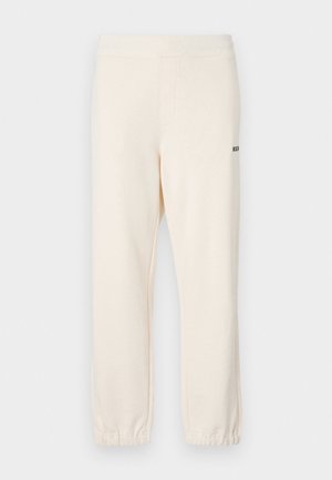 Crème kleurige joggingsbroek met elastische tailleband en boorden, voorzien van zijzakken en een klein zwart logo op de achterkant.
