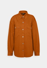 Chemise en denim orange avec un col pointu, deux poches poitrine et des fermetures à boutons argentés. Manches longues avec poignets boutonnés.