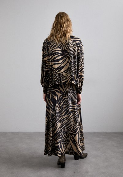 Beige and black zebra print dress with long sleeves, relaxed fit, and flowing maxi length. It features soft, smooth fabric and elastic cuffs.