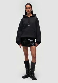 Czarna rozpinana bluza z dużymi rękawami, w zestawieniu z czarną mini spódnicą z sztucznej skóry i czarnymi kozakami do kolan z srebrnymi akcentami hardware.