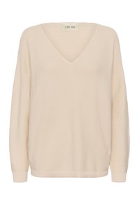 Pull en maille de couleur crème avec un col en V, des manches longues et des poignets côtelés. Le tissu présente une finition texturée, offrant un aspect doux.