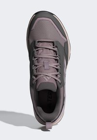 Zapato de senderismo de color púrpura claro con suela de goma negra, parte superior de malla y cordones seguros. Presenta un collar acolchado y una puntera texturizada.
