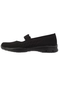 Czarne buty wsuwane wykonane z materiału dzianinowego, charakteryzujące się niskim profilem, teksturowaną cholewką oraz elastyczną podeszwą z rowkami zapewniającymi przyczepność.