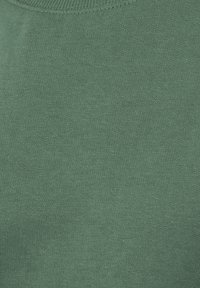Primer plano de una tela de punto verde que muestra una textura de costura fina, ajustada y uniforme.