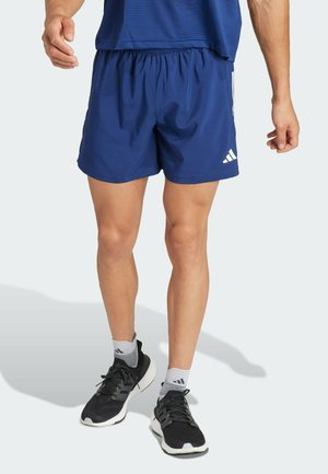 Marineblaue Sportshorts mit elastischem Bund, die eine glatte Textur und ein minimalistisches Design aufweisen, akzentuiert durch ein weißes Logo.