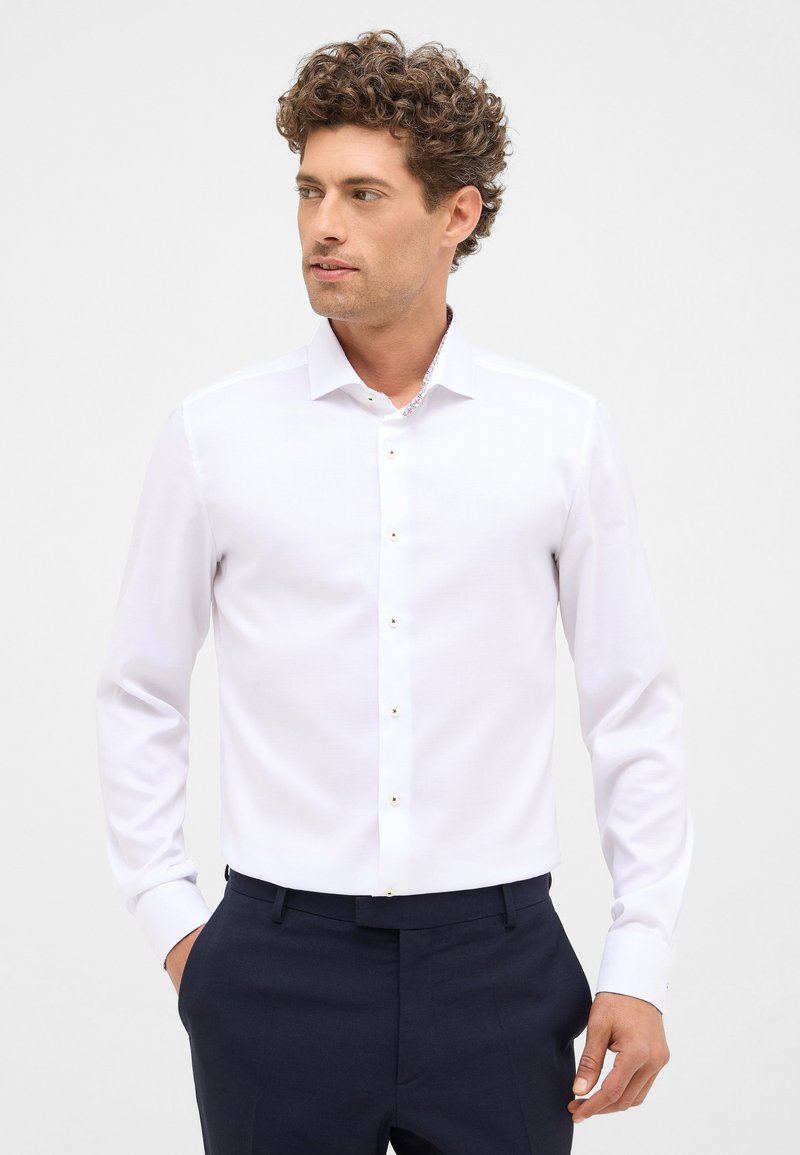 Witte lange mouwen overhemd met een klassieke kraag en knopenfront met gouden hardware. Soepele stof met een slim fit ontwerp. Donkere broek zichtbaar.