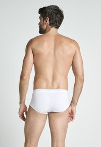 Vita bomullsunderkläder med mjuk textur, med en midjeband märkt "JOCKEY" i ett subtilt mönster. Designen är klassisk och åtsittande.
