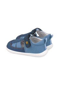Zapatos de tela azul con diseño de punta cerrada, con una correa de gancho y bucle, suela blanca y acentos en azul oscuro contrastante.