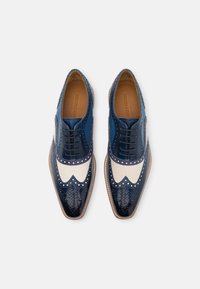 Scarpe brogue in pelle blu con dettagli in tela bianca, caratterizzate da rifiniture perforate e un design classico a punta d'ala. Texture liscia e suole resistenti.