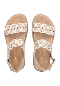 Sandalias de color beige claro con cintas trenzadas y una plantilla texturizada. Material suave, correa ajustable para el tobillo y suela curva para mayor comodidad.