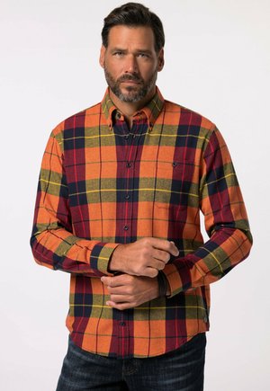 Camisa de franela en cuadros naranjas, rojos y marinos con cuello abotonado, bolsillo en el pecho y mangas largas. Textura suave con costuras visibles.