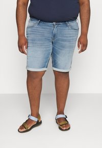 Světle modré džíny kraťasy s ohrnutými lemy, s klasickým designem pěti kapes. Kombinované s plochými sandály s pásky v různých barvách.