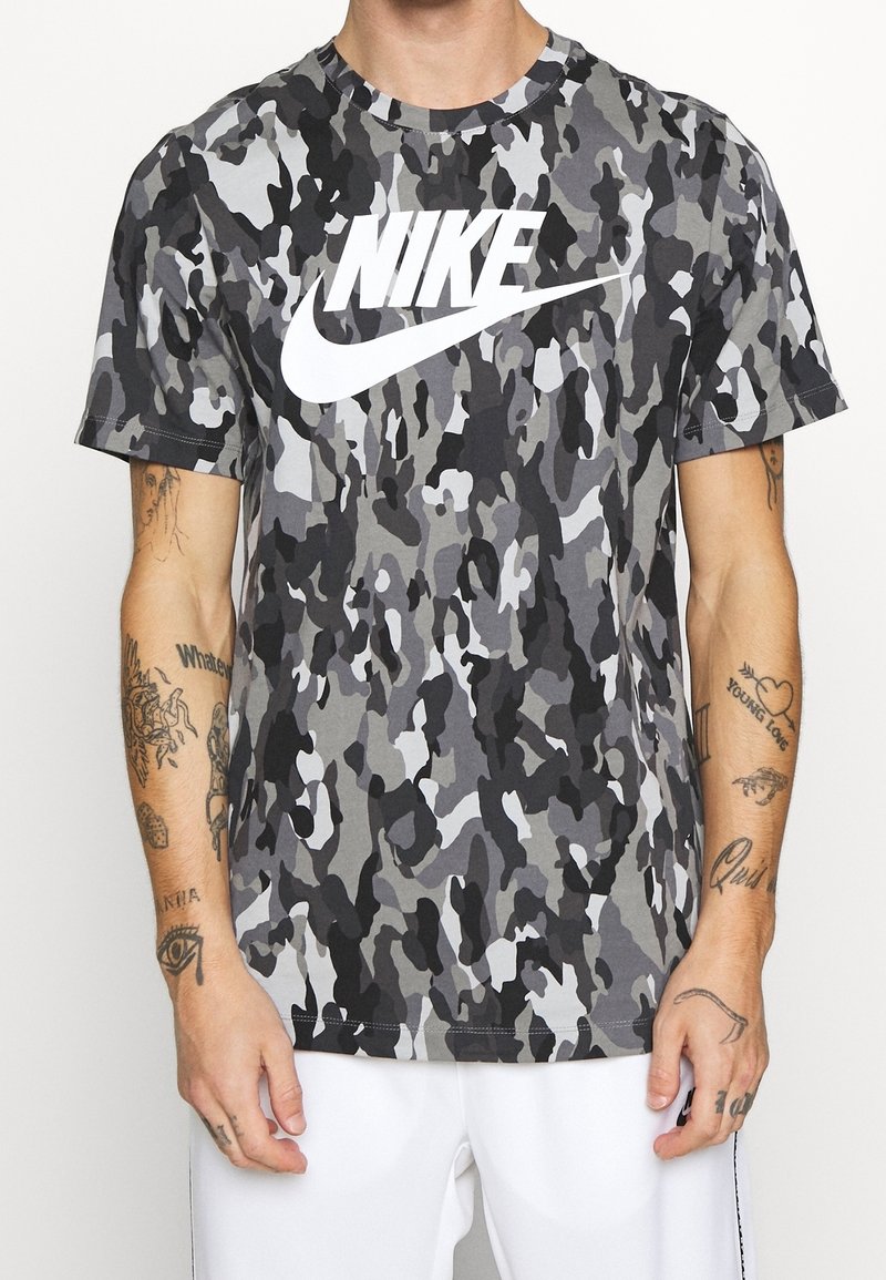 Grå kamouflage kortärmad t-shirt med en stor vit Nike-logotyp på framsidan, gjord av en lätt bomullsblandning.