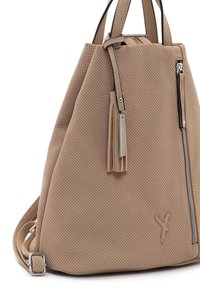 Sac à dos en cuir beige perforé avec poignées supérieures, poche avant verticale zippée, breloque pompon et bretelles réglables.
