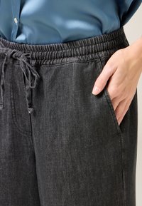 Schwarze Denim-Jogginghosen mit einem elastischen Bund, Kordelzug und seitlichen Taschen, die eine glatte Textur und subtile Steppnähte aufweisen.