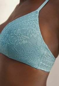 Spitzen-Bralette in sanftem Blaugrün mit Blumenmuster. Verstellbare Träger und glatte Textur erhöhen den Komfort und die Passform. Nahtloses Design und zarte Details.