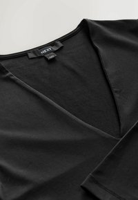 Czarny top z dekoltem w serek wykonany z gładkiej bawełnianej tkaniny. Posiada minimalistyczny design, miękką fakturę oraz metkę z napisem 'NEXT' przy dekolcie.