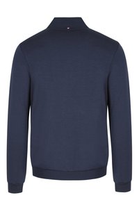 Sudadera azul marino con cuello, puños y dobladillo acanalados. Presenta un pequeño acento en rojo, blanco y azul en la parte posterior del cuello. Textura suave.