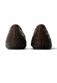 Dark brown woven leather slip-on shoes with flat black soles, shown from the back on a white background.