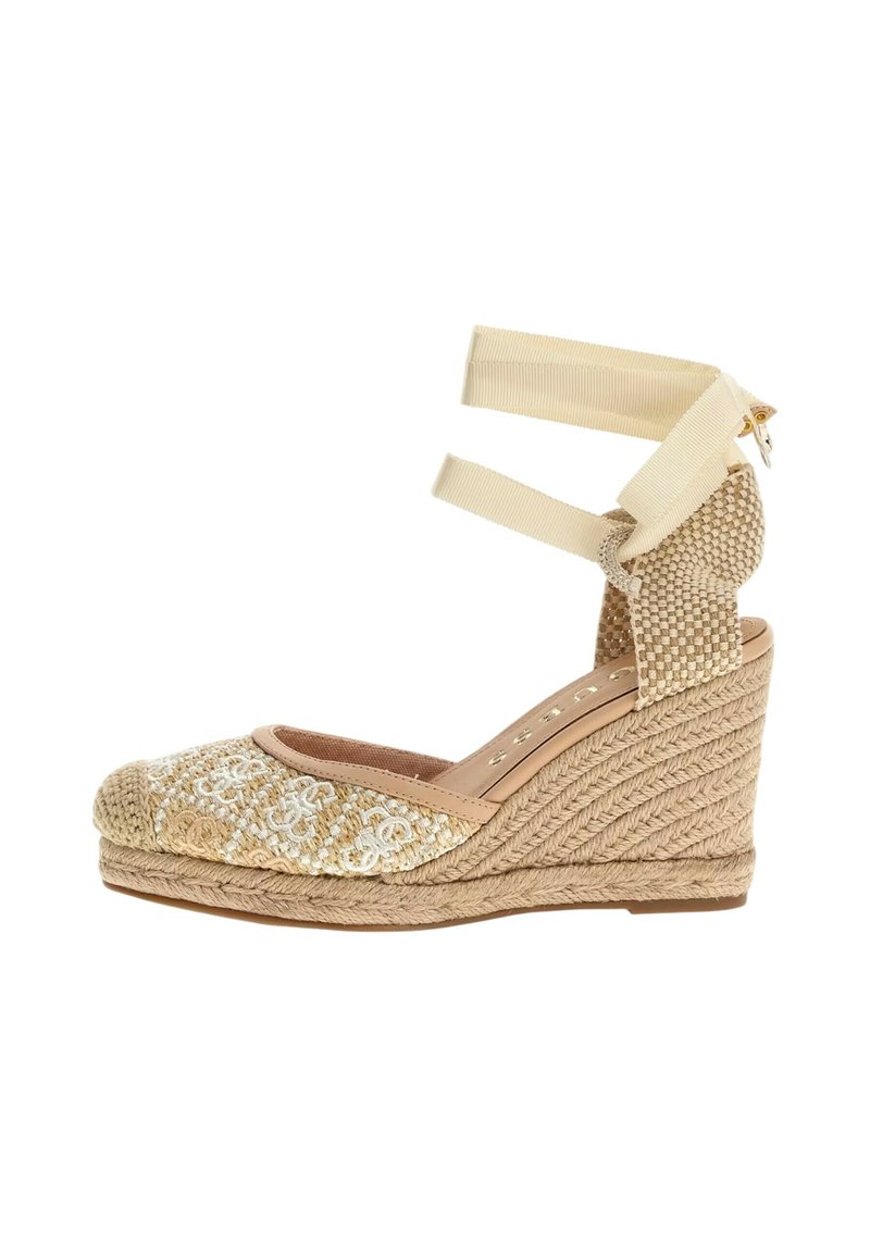 Espadrille con cuña y parte superior de tejido beige, correas de tobillo ligeras y suela de cuerda texturizada. Presenta bordado decorativo en la punta.
