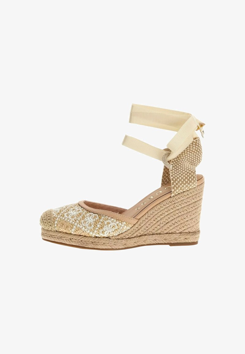 Espadrille con cuña y parte superior de tejido beige, correas de tobillo ligeras y suela de cuerda texturizada. Presenta bordado decorativo en la punta.