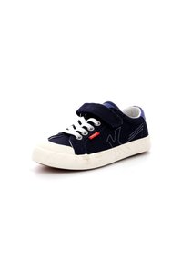 Zapatilla de lona navy con puntera y suela de goma blanca. Presenta cordones mixtos y una correa de Velcro, con un acento de logo en el lado.