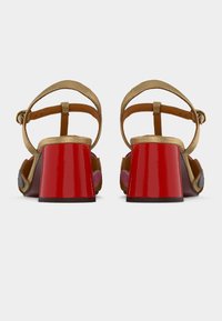 Sandales à brides dorées avec un talon bloc rouge brillant. Confectionnées en cuir et textile. Bride de cheville ajustable pour un meilleur maintien.