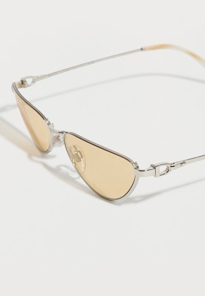 Γυαλιά ηλίου aviator με ασημένια σκελετό, φακούς με ελαφριά κεχριμπαρένια απόχρωση και λεπτούς, ελαφρώς καμπυλωτούς βραχίονες, πάνω σε λευκό φόντο.