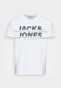 Valkoinen puuvillapaidat, jossa on V-pääntie, ja jossa lukee "JACK & JONES" rohkeilla mustilla ja pisteillä varustetuilla kirjaimilla, korostettuna vaaleansinisillä vaakaraidoilla.