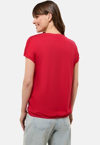 Rode, korte mouwen t-shirt van zacht materiaal met een relaxte pasvorm. Heeft een ronde halslijn en subtiele zijnaaddetails.