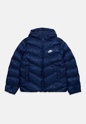 Donkerblauwe Nike pufferjas met capuchon, volledige ritssluiting aan de voorkant, zijzakken en subtiel tonale logopatroon.